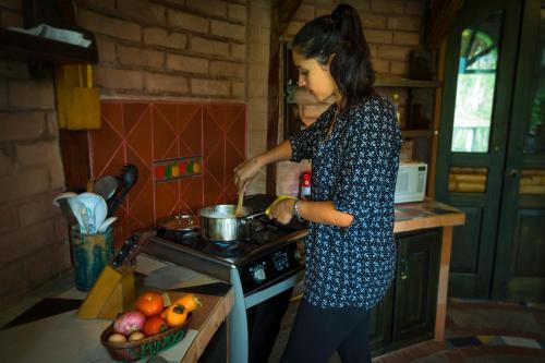 a woman standing in a kitchen cooking in a pot on a stove at Sacha Urco Lodge y Bosque Protector in Mindo