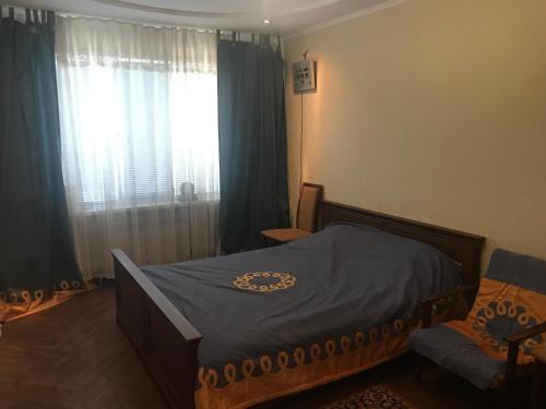 a bedroom with a bed and a window with curtains at Квартира в Тирасполе in Tiraspol