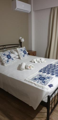 a white bed with blue and white sheets and pillows at Ria's Deluxe Apartments in Faliraki