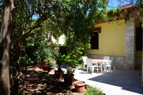 een patio met een tafel, stoelen en bomen bij La Casa del Borgo in Specchia