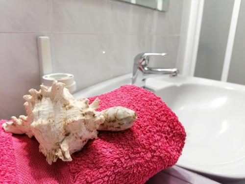 muszla na różowym ręczniku obok umywalki w łazience w obiekcie Mar Holiday Home w mieście Los Cristianos
