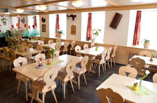 ein Esszimmer mit Tischen und Stühlen und Fenstern in der Unterkunft Hotel Alpina in Unterschächen