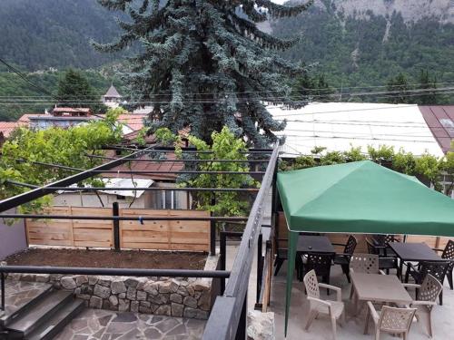 a patio with tables and chairs and a green umbrella at Vaso&Iro Guest House in Borjomi