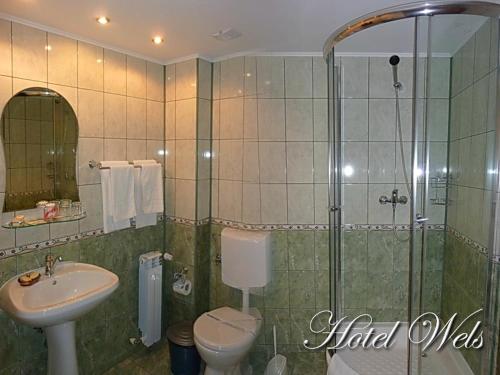 a bathroom with a shower and a toilet and a sink at Hotel Wels in Beştepe