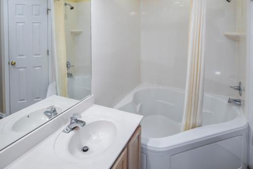 a white bathroom with a sink and a shower at The Suites at Fall Creek in Branson