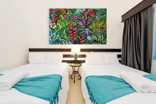 two beds in a room with a painting on the wall at Seis Playas Hotel in Tamarindo