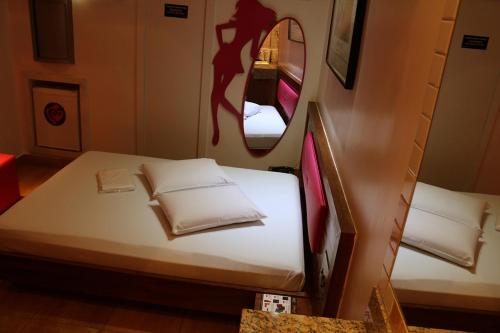 ein kleines Schlafzimmer mit einem Bett und einem Spiegel in der Unterkunft Auhe Motel (Adults only) in Betim
