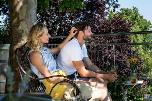 a man and woman sitting on a bench talking on a cell phone at Familienweingut Oberer Germuth in Leutschach