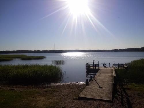 a dock on a lake with the sun in the sky at Majvik Congress Hotel in Kirkkonummi