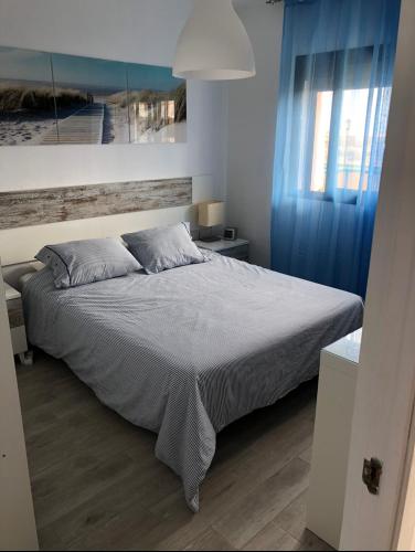a bedroom with a large bed with blue curtains at Sand Dunes & Sun - Dunasol in Corralejo