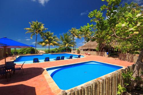 einen Pool in einem Resort mit einem Tisch und Stühlen in der Unterkunft Pousada Barra Velha in Maragogi