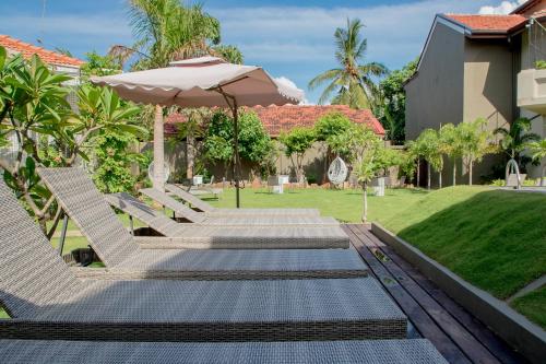 a patio with chairs and an umbrella and a lawn at Seahorse Hotel & Spa in Negombo
