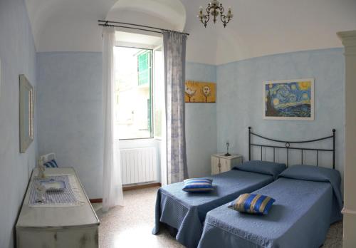 a bedroom with two blue beds and a window at Ciassa Noeva in Pieve di Teco