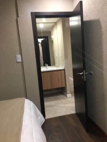 a bathroom with a door open to a bathroom with a sink at Michelle- Departamentos in Necochea