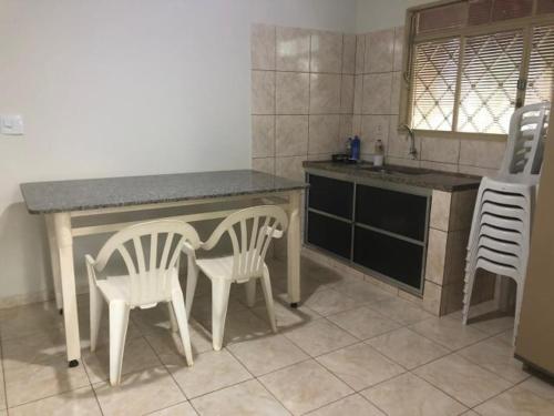 une cuisine avec deux chaises, une table et un comptoir dans l'établissement Cantinho do Folclore, à Olímpia