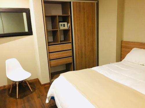 a bedroom with a white bed and a white chair at Michelle- Departamentos in Necochea