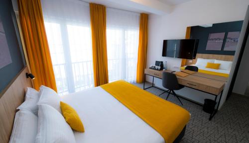 a hotel room with a bed and a desk with a computer at City Inn in Pristina