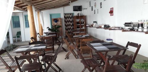 a group of wooden tables and chairs in a restaurant at Pousada Vila Mar in Itaúnas