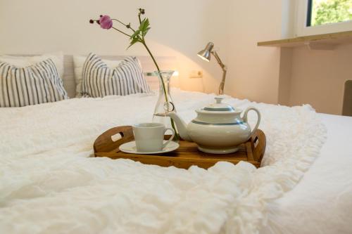 uma bandeja com um bule de chá e uma chávena numa cama em hoamelig em Batschuns