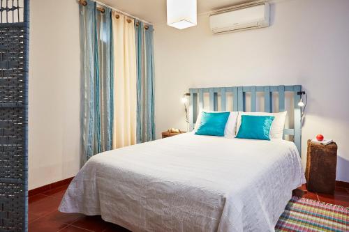 um quarto com uma cama grande e almofadas azuis em Casa da Sobreira em Sobral de São Miguel