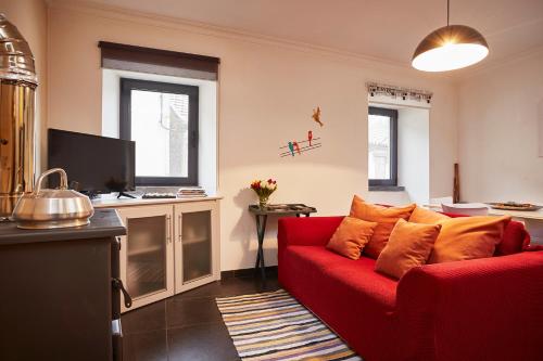 a living room with a red couch and a tv at Casa da Sobreira in Sobral de São Miguel