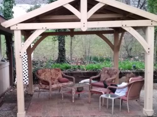 a wooden pergola with chairs and a girl laying on a patio at The Iris Garden Downtown Cottages and Suites in Nashville