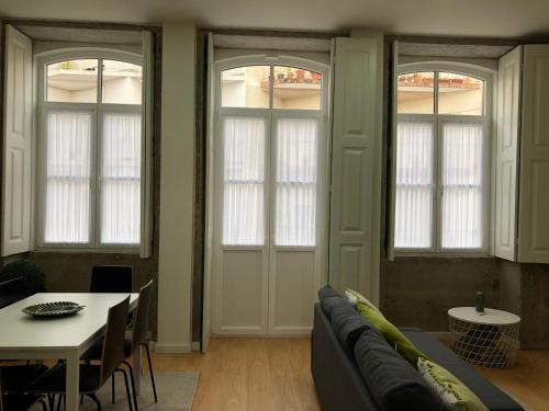a living room with a couch and a table and windows at Carmo House in Braga