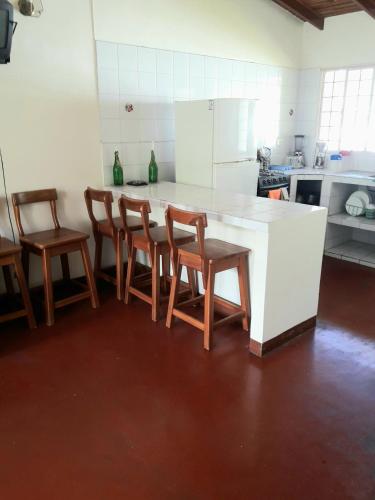 a kitchen with a white counter and wooden chairs at Casas Vacacionales La Cima in Mérida