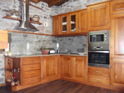 a kitchen with wooden cabinets and a stove at Casa do Pelourinho in Rebordainhos