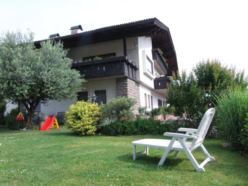 a white chair sitting in the grass in front of a house at Garni Runggner Traubenhof in Termeno