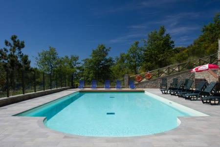 una grande piscina con sedie e ombrellone di Country House Vezzano a Chiusi della Verna