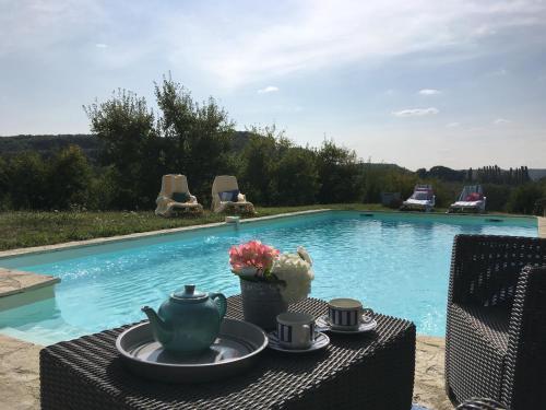 une table avec une théière dessus à côté d'une piscine dans l'établissement Domaine des pruniers, à Valeilles