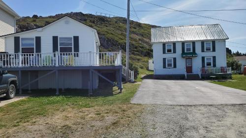 a white house and a house with a porch at Hillside Cottage 1 in Twillingate