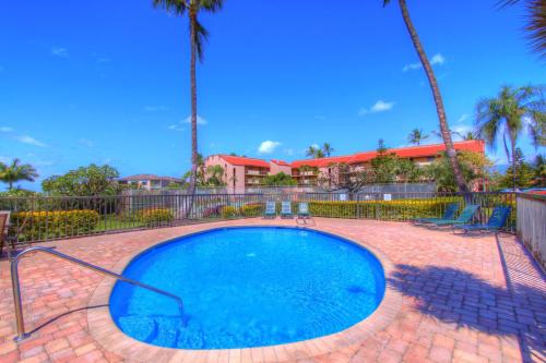 a small swimming pool with a fence and palm trees at Maui Vista 1313 in Kihei