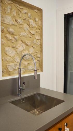 a sink in a kitchen with a stone wall at Can Nicasi in L'Escala
