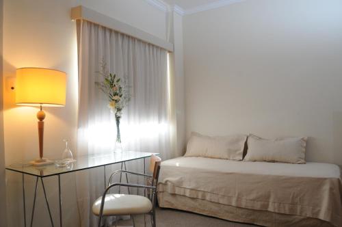 1 dormitorio con 1 cama y 1 mesa con lámpara en Parra Hotel & Suites en Rafaela
