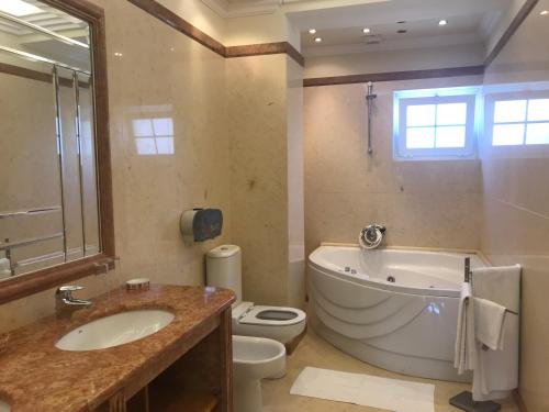 a bathroom with a tub and a toilet and a sink at Atlantic Waves Accommodation ~ Carcavelos Beach in Carcavelos