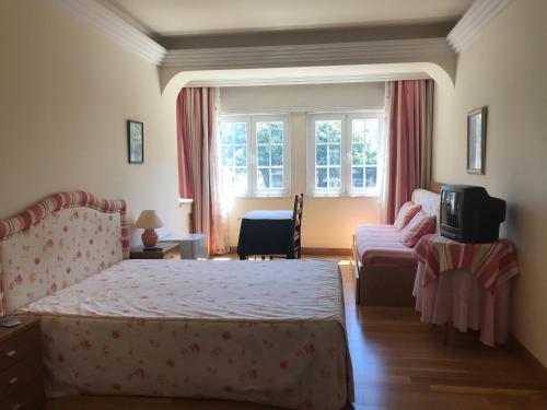 a bedroom with a bed and a couch and a tv at Atlantic Waves Accommodation in Carcavelos