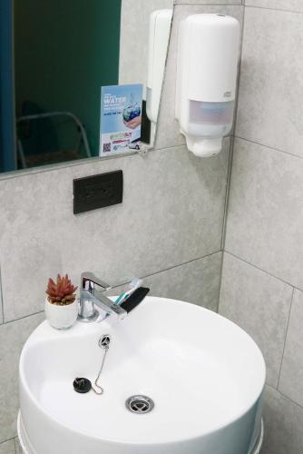 a bathroom with a white sink and a mirror at NATIVUS Art-Hostel in San José