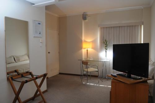 a living room with a flat screen tv and a bed at Parra Hotel & Suites in Rafaela