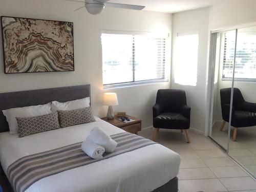 a bedroom with a large white bed and a chair at Direct Hotels - North Shore Kawana in Kawana Waters