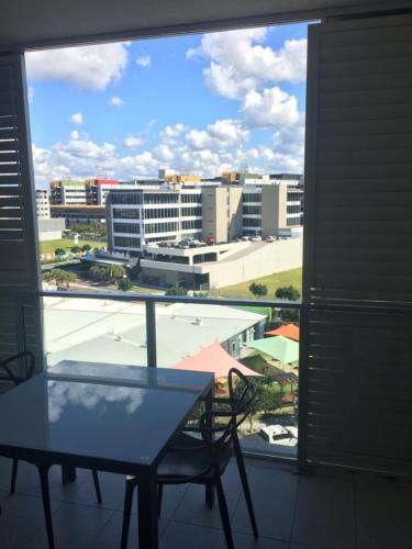 a table and chair on a balcony with a view of a city at North Shore Oceanside Kawana in Kawana Waters