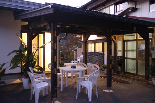 a wooden pergola with a table and chairs on a patio at Kozaemon in Gujo