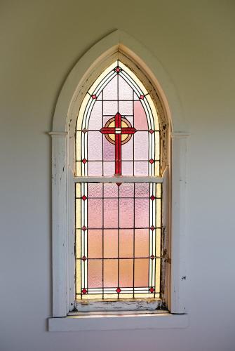 a stained glass window with a cross on it at Seacroft Estate in Apollo Bay