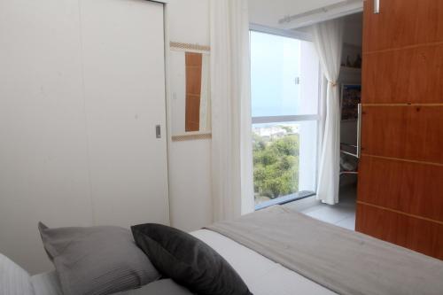 a bedroom with a bed and a large window at Encantos do Porto da Barra in Salvador
