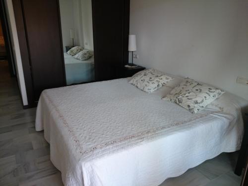 a bedroom with a white bed with pillows on it at Apartamento Ayamonte golf Costa Esuri in Ayamonte