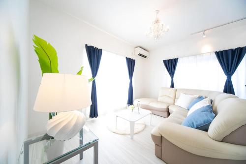 a white living room with a white couch and blue pillows at Awaji Seaside Resort in Iwaya 3000 in Awaji