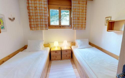 Duas camas num pequeno quarto com uma janela em Giant 2 em St. Moritz