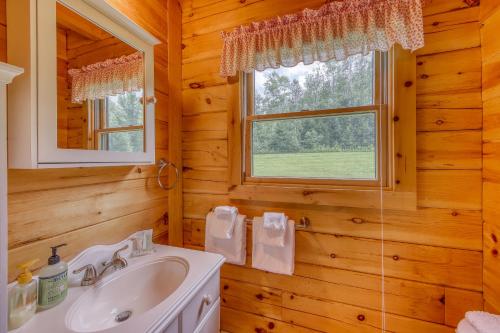 Un baño con lavabo y ventana. en Log Cabin Escape, en Jacksonville
