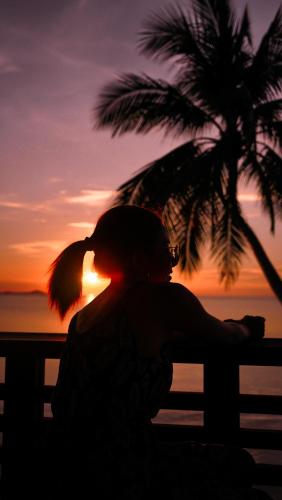 a woman sitting on a bench watching the sunset at Tango Luxe Beach Villa, Koh Samui in Choeng Mon Beach